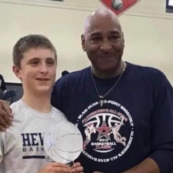 St. John's alum and black entreprenuer, standing with a young boy smiling 
